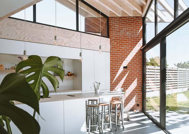 Projectbeeld Woning R&A Oostkamp: hedendaagse rode baksteenarchitectuur, rijk gestructureerde gevel met perforaties, herfststemming met bladeren op de voorgrond.